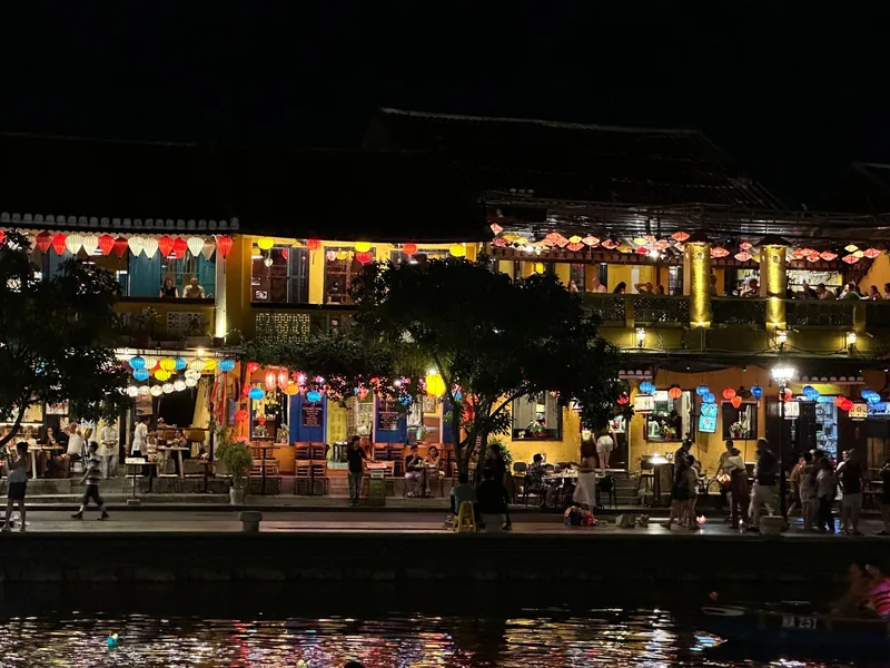 Những ngôi nhà ven sông rực rỡ đèn lồng về đêm ở phố cổ Hội An, du khách dạo bước dọc bờ sông.