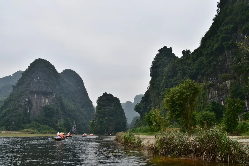 Những chiếc thuyền nhỏ chở du khách trên dòng sông giữa các núi đá vôi ở Tràng An, Ninh Bình.